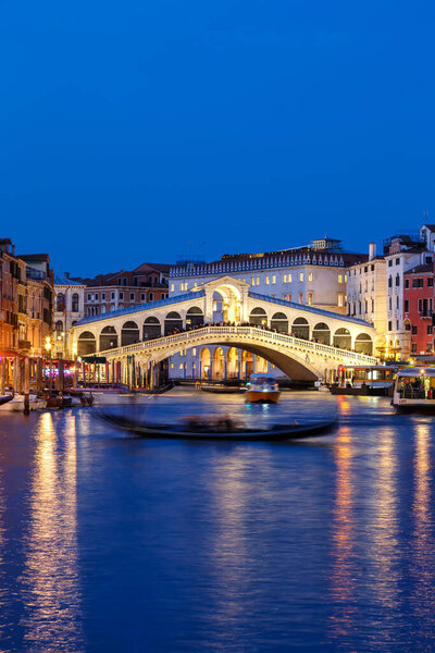 Venice Rialto bridge over Canal Grande with gondola travel traveling holidays vacation town city portrait format at night in Italy