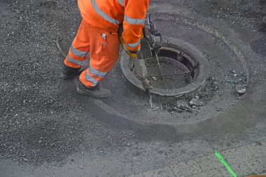 Turuncu elbiseli, hidrolik çekici olan asfalt yol işçisi.
