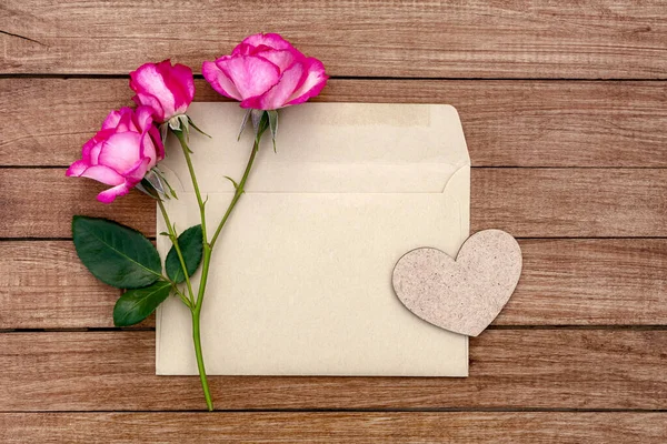 Tahta Arka Planda Kalbi Olan Bir Zarfın Içinde Pembe Güller — Stok fotoğraf