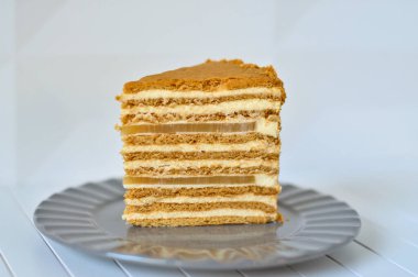 Side view of a Piece of Honey Cake with two layers of pear marmalade staying on a plate