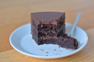Piece of delicious chocolate cake with three layers of dark biscuits with detached piece