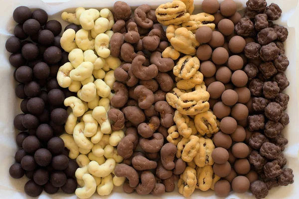 Six types of chocolate covered nuts in vertical rows.