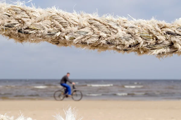 Closeup thick rope and cyclist go sea coast beach — Stock Photo, Image