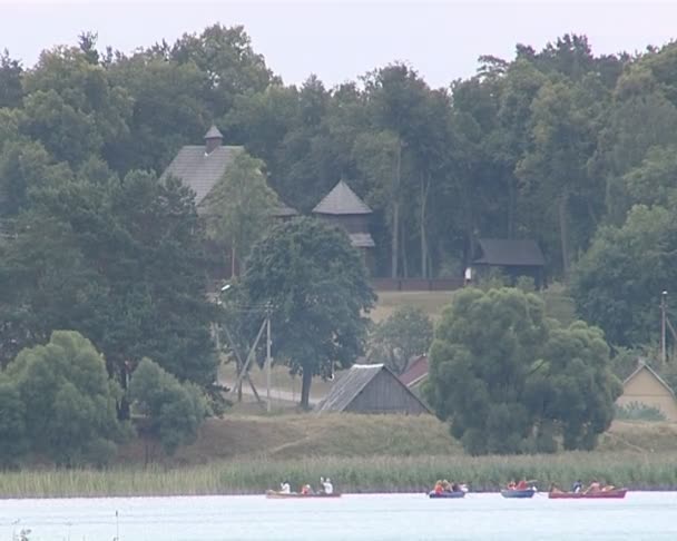 Sjöstranden. krusade vatten, vass, båtar i avstånd och gull. — Stockvideo