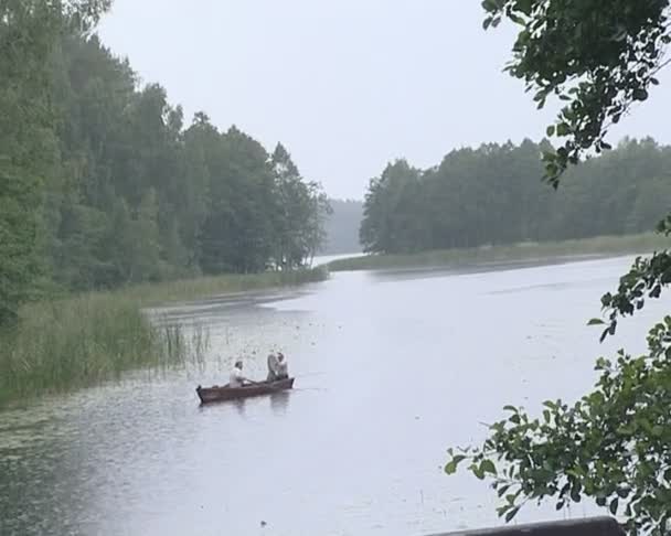 Veneen matkustajat kiinni sateessa purjehtiessaan pitkin jokea veneessä . — kuvapankkivideo