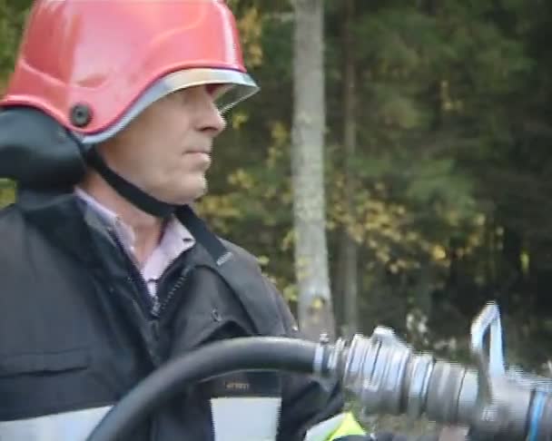 Uniformed firefighter with the hose in the hands fighting fire. — Stock Video