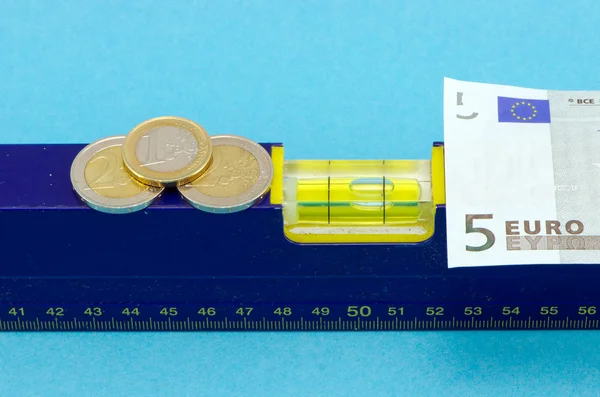 Outil de niveau pièce de billet en euros sur bleu — Photo