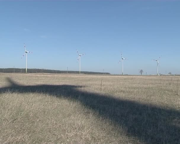 Sombra de molino de viento giratorio en tierra y molino de viento en distancia . — Vídeo de stock