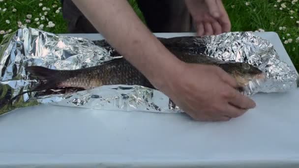 Envelopper à la main papier d'aluminium de poisson cuire — Video