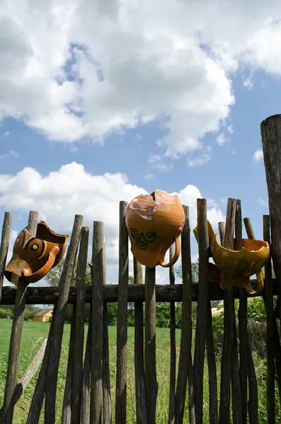 Clay broken pitchers hang wooden rural woven fence — Stock Photo, Image