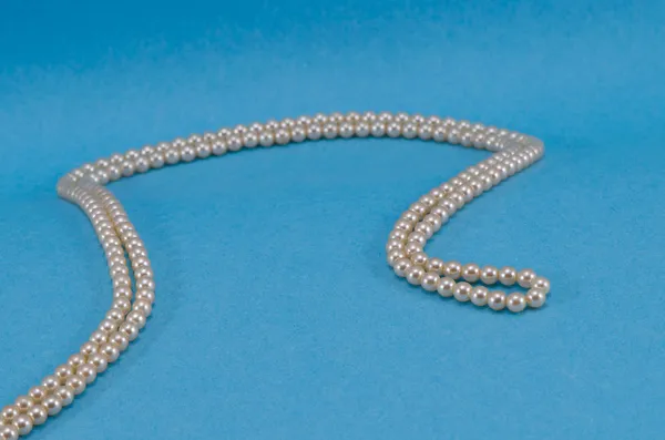 Collar de perlas collar a su vez primer plano fondo azul — Foto de Stock