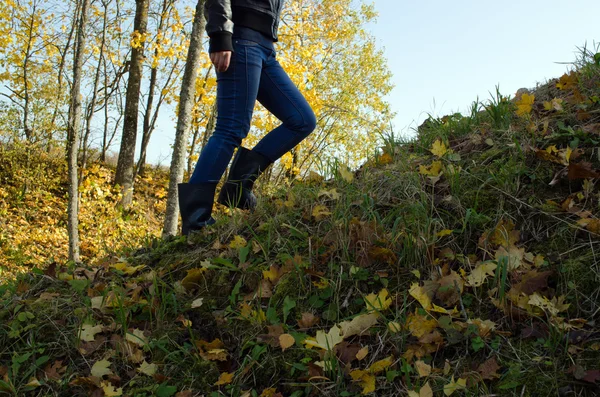 Tjej klättra hill rubber boot hösten träd lämnar — Stockfoto