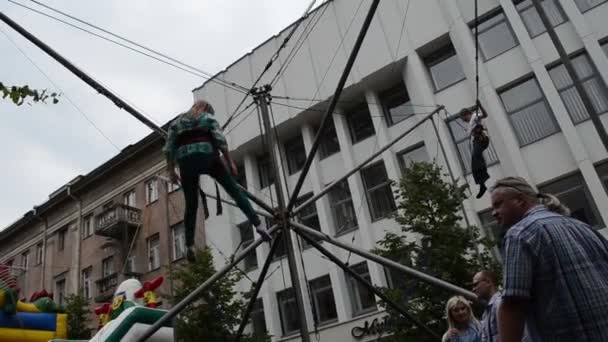 Niños niña niño salto con cinturón de seguridad en trampolín en el patio de recreo — Vídeo de stock