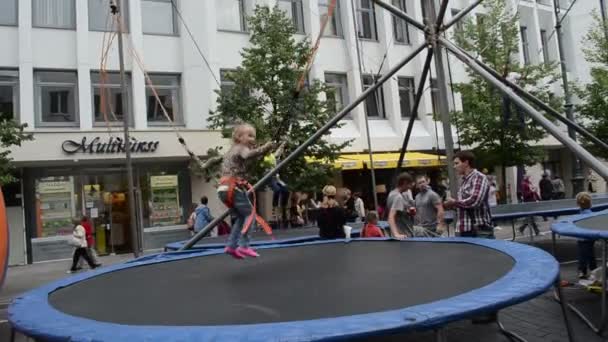 Kids girl boy jump with safety belt on trampoline in playground — Stock Video