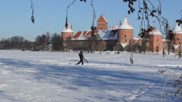 Člověk nést lyžařské zmrazené jezero trakai castle zimní aktivní rekreace — Stock video
