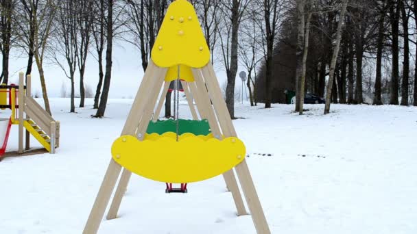 Nahaufnahme gelb Schaukel Spielzeug bewegen Winter Spielplatz bedeckt Schnee — Stockvideo