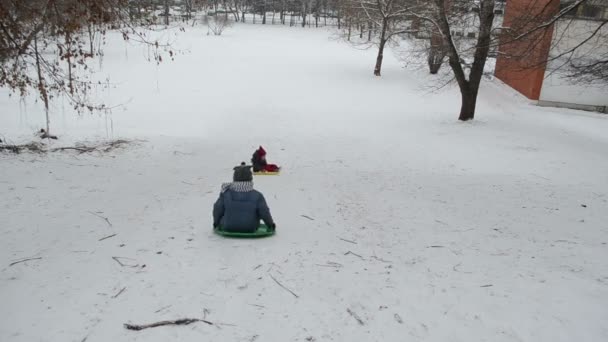 Duas crianças descendo colina íngreme com neve almofada agradável tarde de inverno — Vídeo de Stock