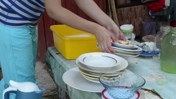 Hände waschen schmutziges Geschirr auf dem Dorftisch — Stockvideo