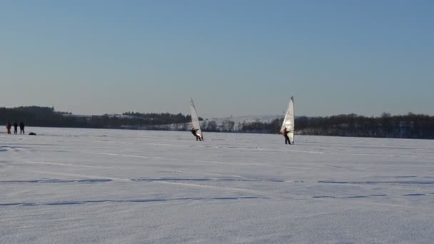 Follow two ice surfers men sail frozen lake snow extreme sport — Stock Video