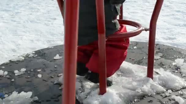 Niña en el patio de recreo está girando círculo rojo en invierno — Vídeo de stock