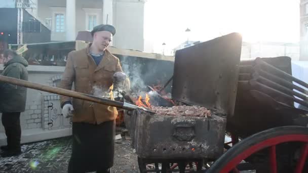 Hombre hornear carne picar leña primavera calle fuego justo humo — Vídeo de stock