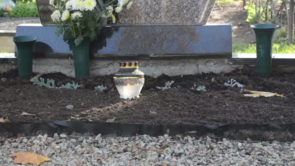 Kaars glazen pot branden in de buurt van graf obelisk kerkhof — Stockvideo