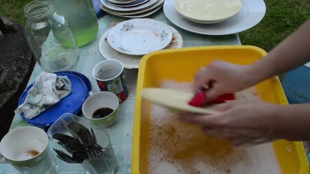 Руки мыть грязную посуду на деревенском столе — стоковое видео