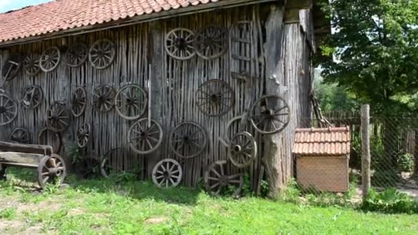 Ретро візок колеса висять на сільській будівельній стіні лавки — стокове відео