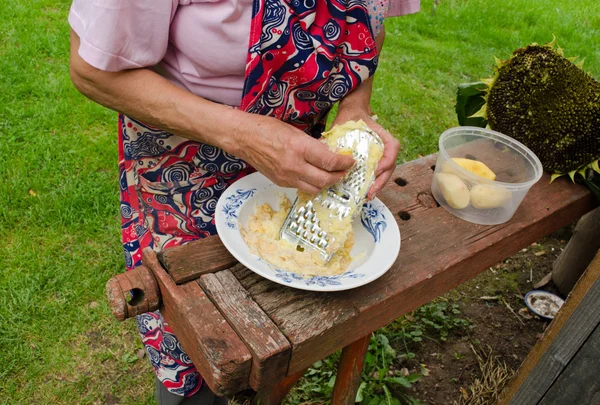 Sênior mulher ralar casca batatas triturador de aço — Fotografia de Stock