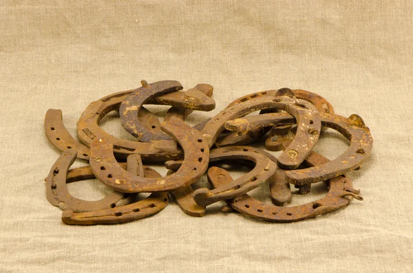 Stack old retro rusty horseshoes linen background — Stock Photo, Image