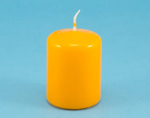 Amarillo cera gruesa vela mecha fondo azul — Foto de Stock