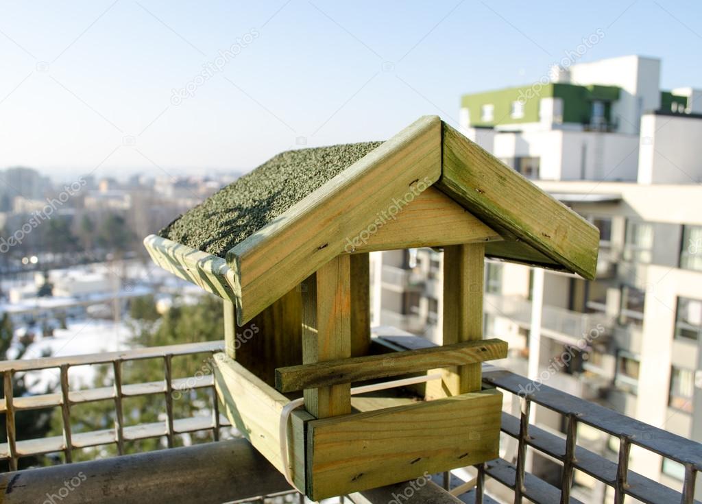 wooden small bird feeder on the balcony edge