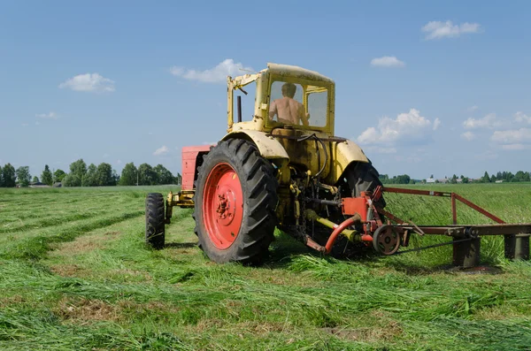 拖拉机割草使弯曲在草地上 — 图库照片