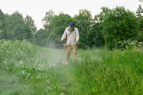 Працівник людина вирізати обробкою mow мокрій траві після дощу — стокове фото