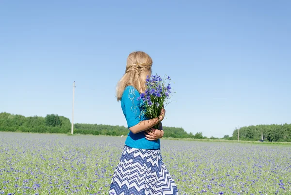 Menina com buquê azul em ampla vista para trás prado — Fotografia de Stock
