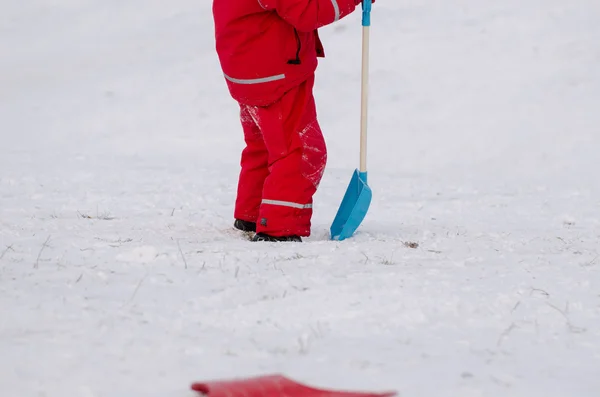 Kind stand met sneeuw schop in waterdichte slijtage — Stockfoto