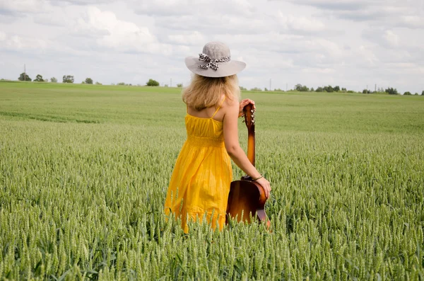 Back view of women with guitar in wide rye field — Stock Photo, Image
