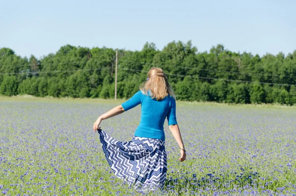 Flicka med blå kjol dans i blåklint äng — Stockfoto