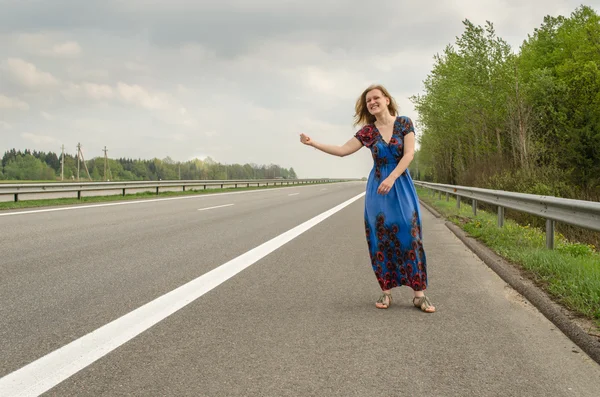 Piękna dziewczyna autostopem na drodze — Zdjęcie stockowe