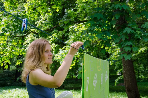 Woman hang laundry on clothesline strings — Stock Photo, Image