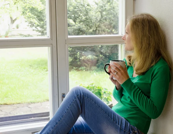 Gebroken hart meisje zitten op venster vensterbank drinken koffie — Stockfoto