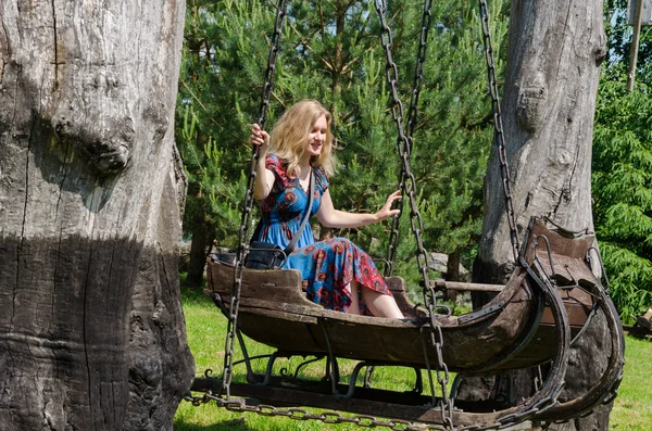 Frau schwingt retro dekorative Schaukeln Holzschlitten — Stockfoto