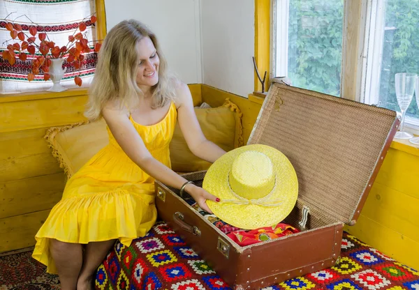 Mujer puso bonito sombrero amarillo en la vieja maleta en la habitación —  Fotos de Stock