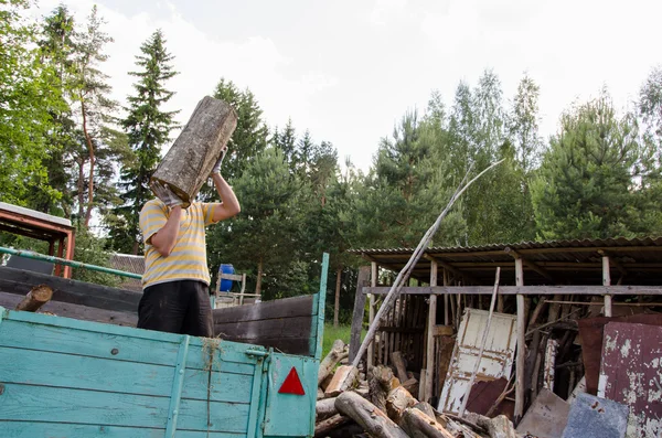 Arbetstagare man lasta träd log ved från trailer — Stockfoto