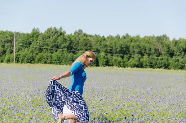 Flicka dansa i ändlösa blåklint äng i sommar — Stockfoto