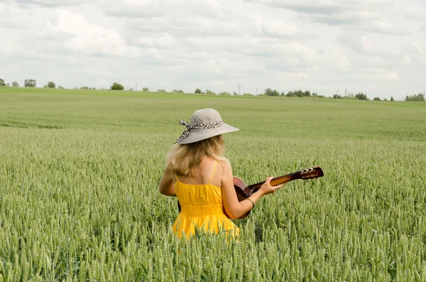 Land meisje in jurk spelen gitaar tarweveld — Stockfoto