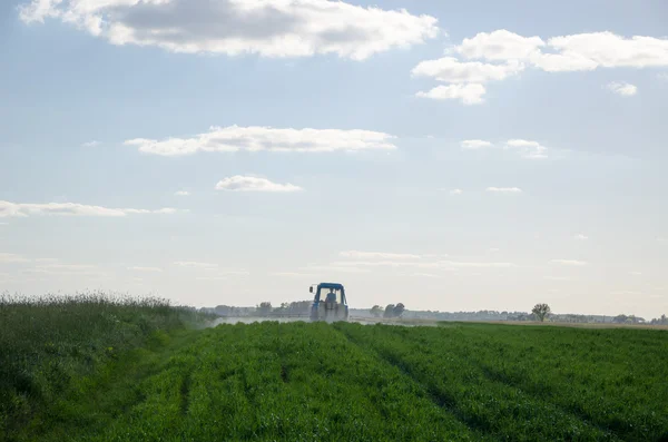 Traktor sprej pole s chemikáliemi a pracovník muž — Stock fotografie