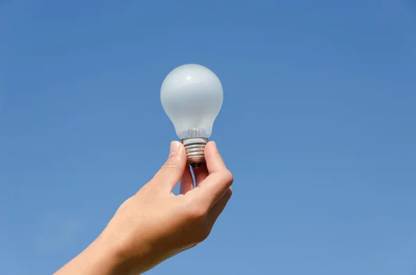 Hand hold light bulb on blue sky background — Stock Photo, Image