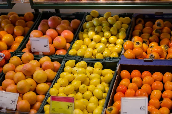 Fresh orange lemon persimmon in plastic boxes — Stock Photo, Image