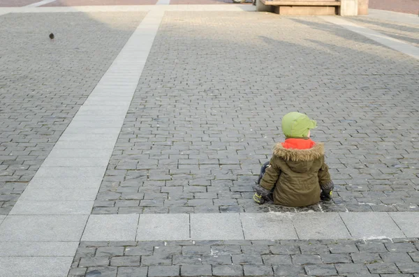 Enfant solitaire assis sur le trottoir dans la vieille ville — Photo